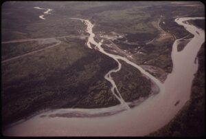 Silty brown rivers in a green Alaska landscape with roads and buildings